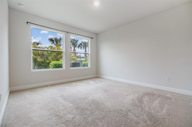 empty room featuring light colored carpet and baseboards