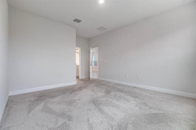 spare room featuring visible vents, light colored carpet, and baseboards