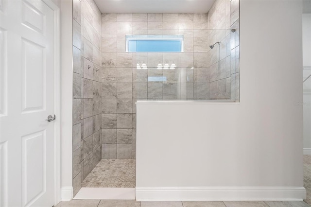 bathroom featuring tile patterned floors, a walk in shower, and baseboards