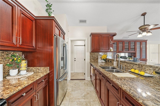 kitchen with visible vents, backsplash, a sink, dark brown cabinets, and stainless steel fridge