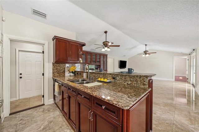 kitchen with reddish brown cabinets, visible vents, a sink, and a peninsula