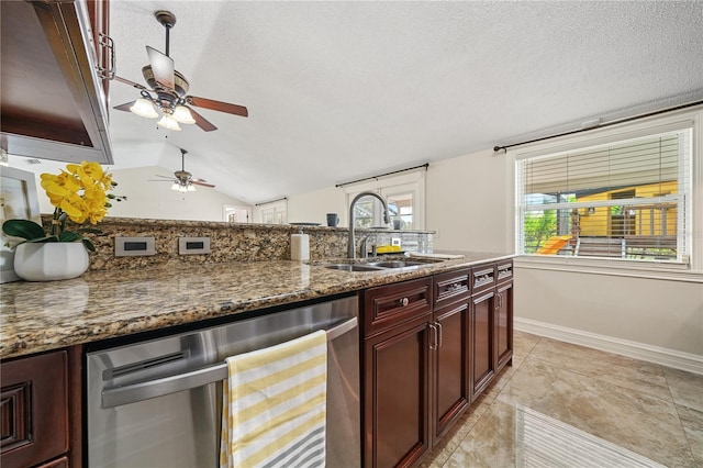 kitchen featuring dark stone countertops, lofted ceiling, a sink, and dishwasher