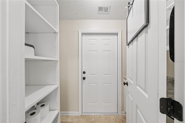 interior space featuring visible vents, a textured ceiling, and light tile patterned floors