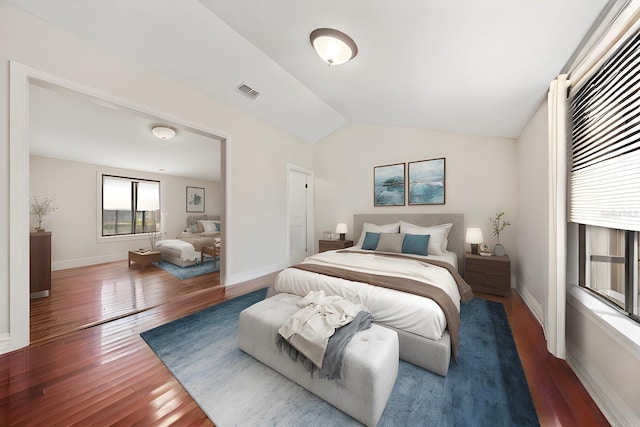 bedroom featuring visible vents, vaulted ceiling, baseboards, and wood finished floors