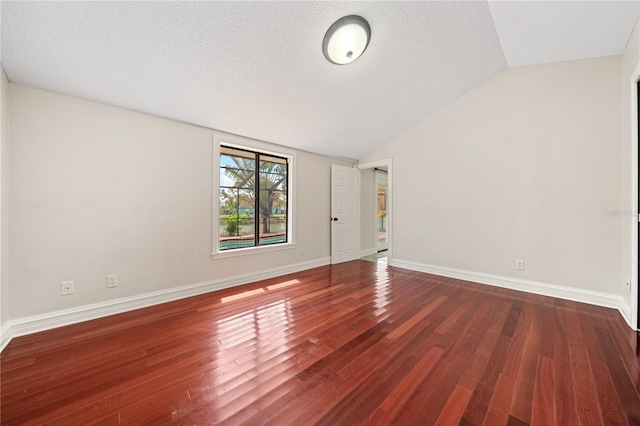 unfurnished room with lofted ceiling, a textured ceiling, baseboards, and wood finished floors