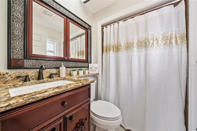 bathroom with toilet, vanity, and visible vents