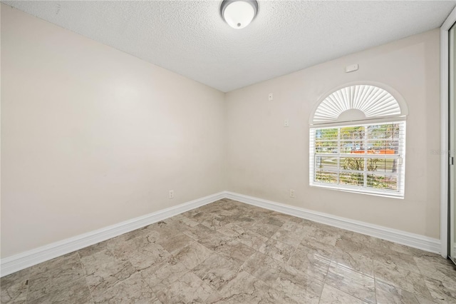 empty room featuring baseboards and a textured ceiling