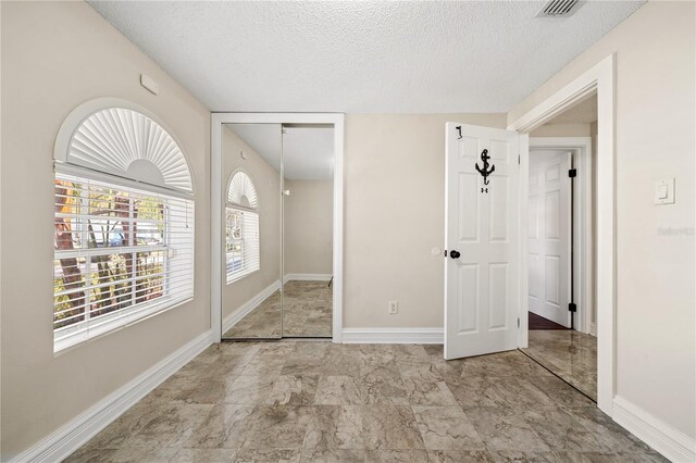 unfurnished bedroom featuring baseboards, a closet, visible vents, and a textured ceiling