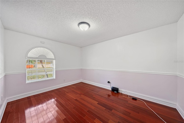 unfurnished room featuring baseboards, a textured ceiling, and hardwood / wood-style floors