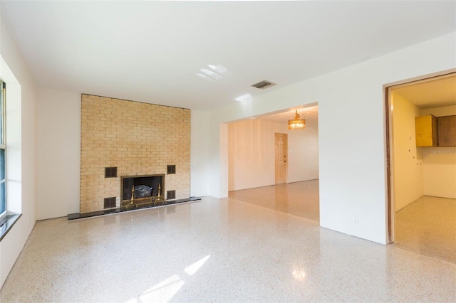 unfurnished living room with visible vents, a fireplace, and speckled floor