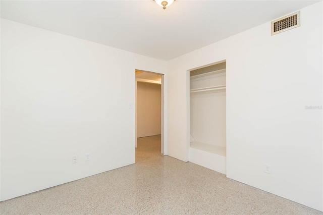 unfurnished bedroom featuring speckled floor, a closet, and visible vents