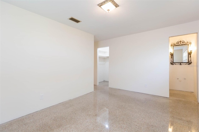 spare room featuring visible vents and light speckled floor