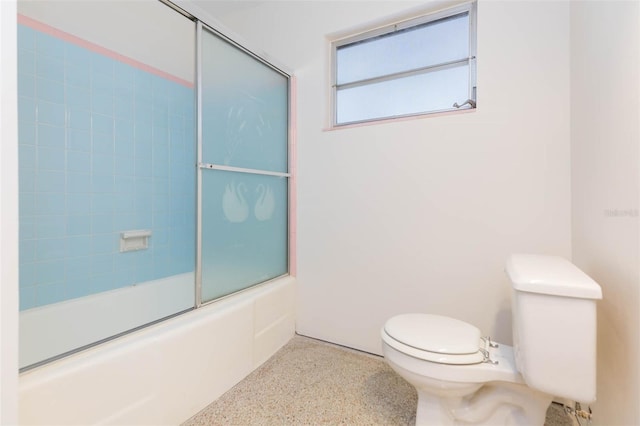 bathroom with speckled floor, shower / bath combination with glass door, and toilet