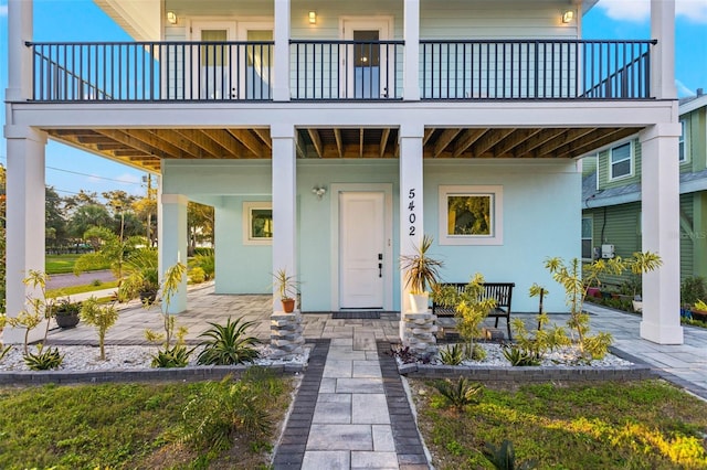 property entrance featuring covered porch and stucco siding