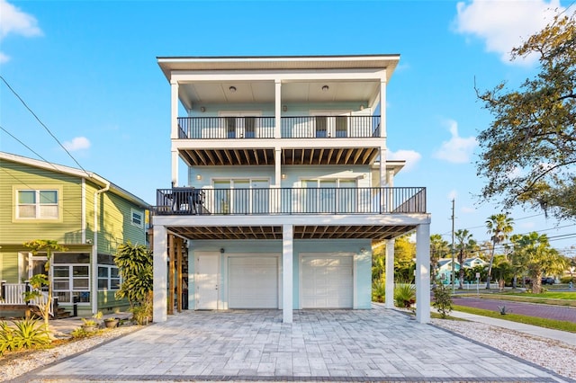 coastal home featuring a garage, a balcony, and decorative driveway