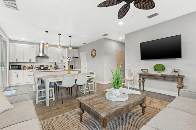 living room with light wood-type flooring, baseboards, visible vents, and recessed lighting