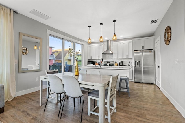 dining space with visible vents, baseboards, and wood finished floors