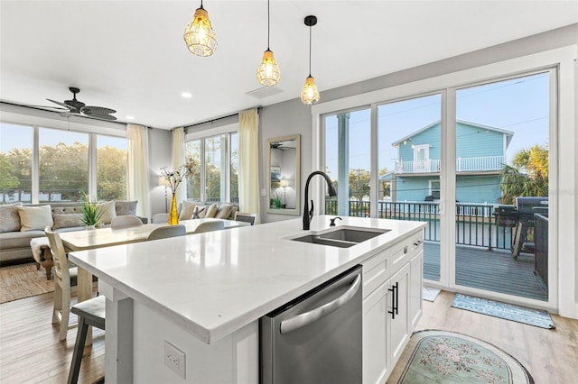 kitchen with dishwasher, open floor plan, light wood-type flooring, pendant lighting, and a sink