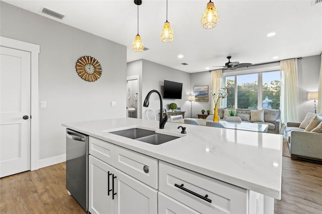 kitchen featuring visible vents, stainless steel dishwasher, open floor plan, a sink, and an island with sink