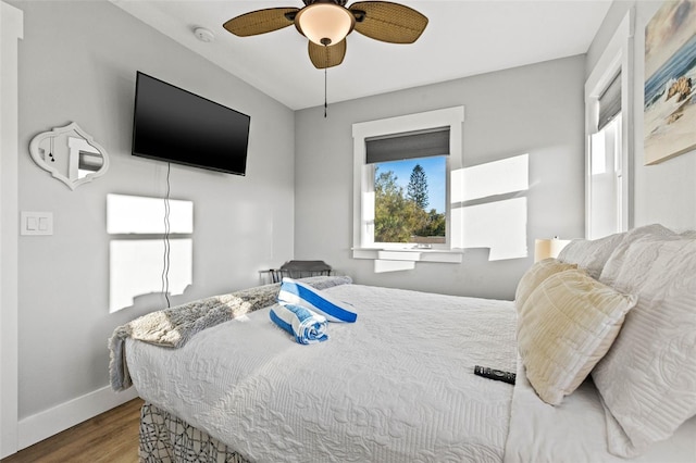 bedroom featuring multiple windows, wood finished floors, a ceiling fan, and baseboards