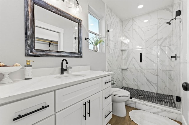 bathroom with vanity, wood finished floors, a shower stall, and toilet