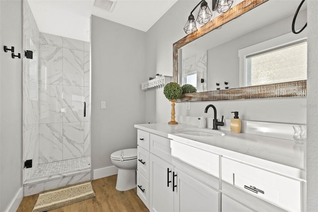 full bath featuring a marble finish shower, visible vents, toilet, wood finished floors, and vanity