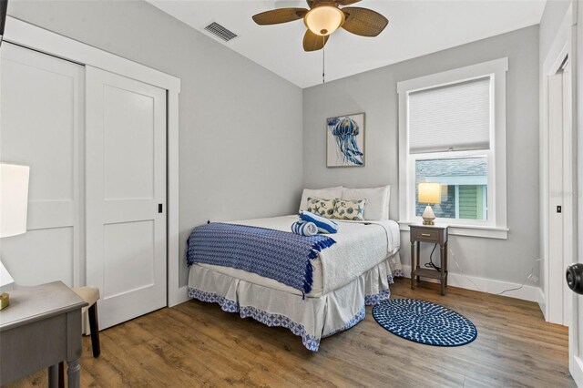 bedroom with a closet, visible vents, ceiling fan, wood finished floors, and baseboards