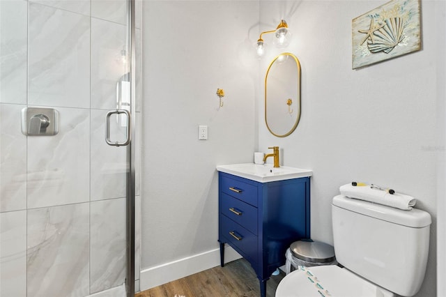 bathroom with baseboards, toilet, wood finished floors, vanity, and a shower stall