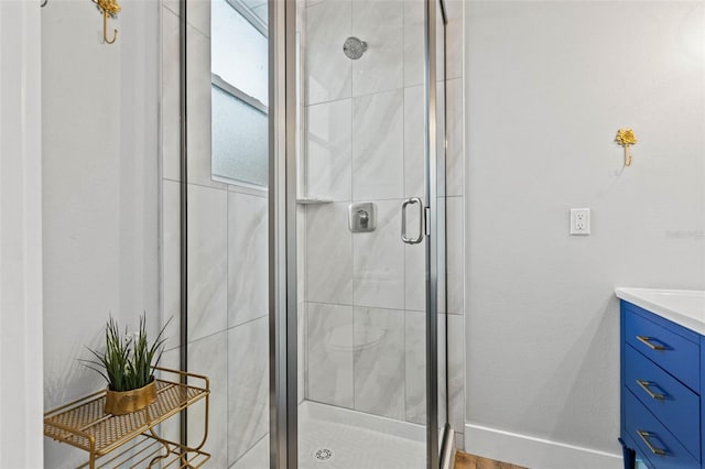 bathroom with a stall shower, vanity, and baseboards