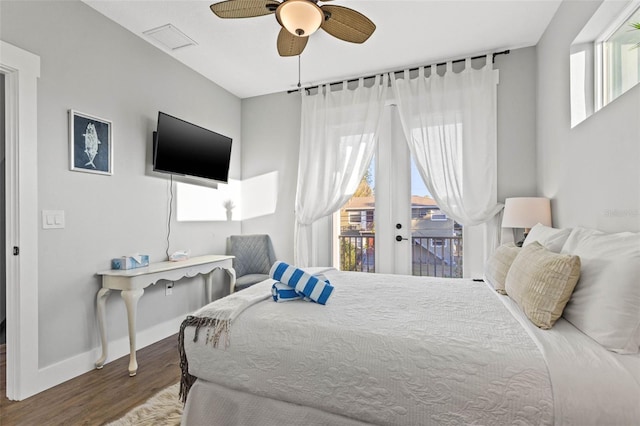 bedroom with baseboards, multiple windows, wood finished floors, and access to exterior