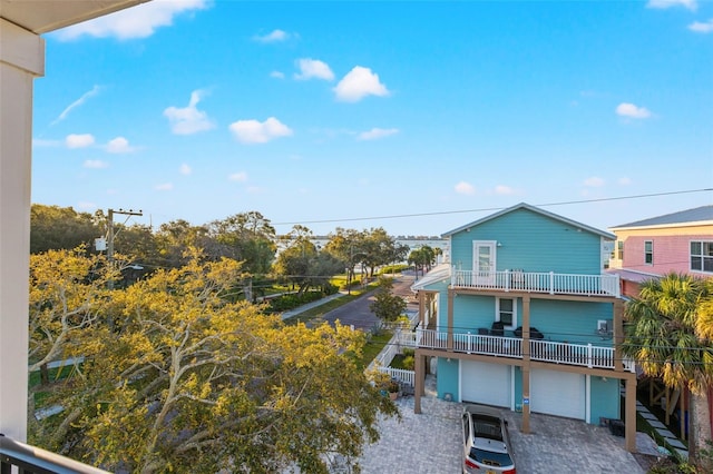 back of house featuring decorative driveway, a balcony, and an attached garage