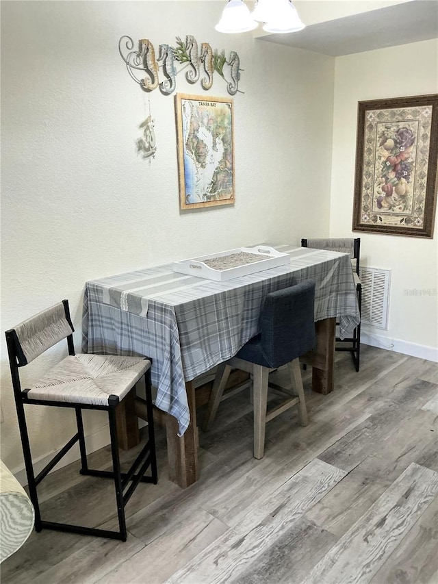 dining space with visible vents, baseboards, and wood finished floors