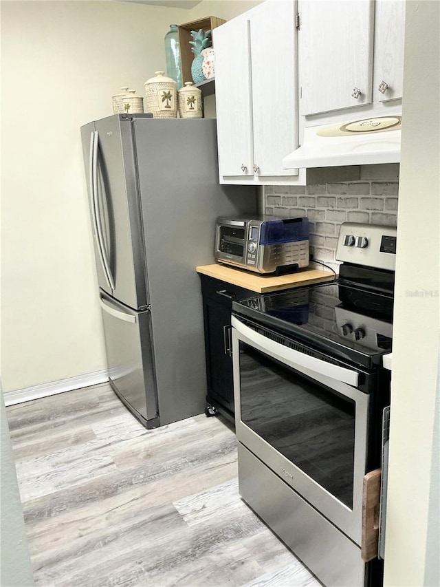 kitchen with light wood-type flooring, under cabinet range hood, backsplash, stainless steel appliances, and light countertops