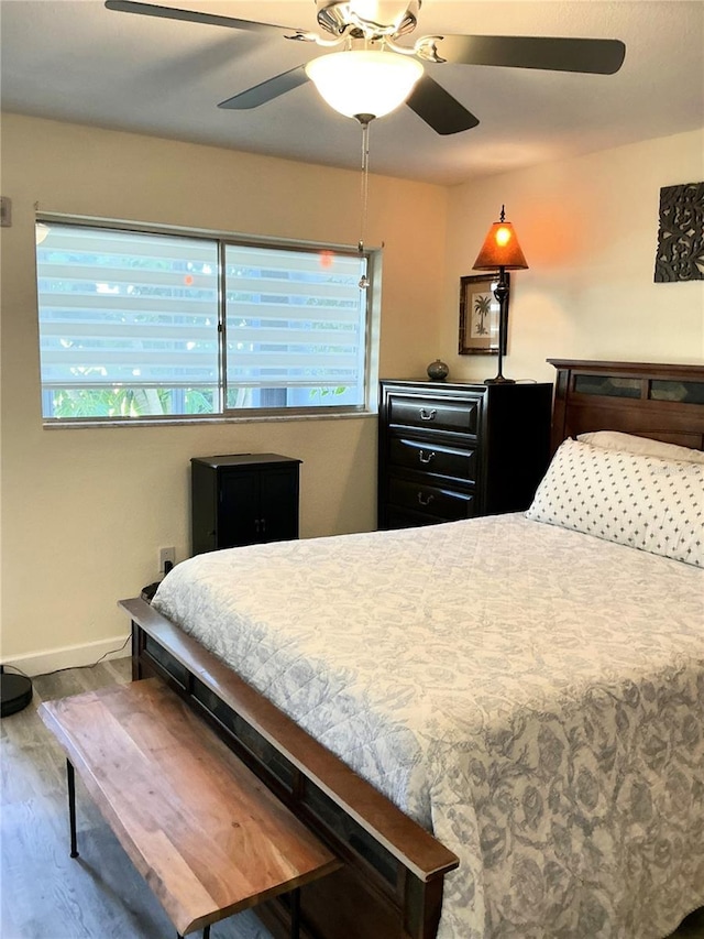 bedroom with baseboards, ceiling fan, and wood finished floors