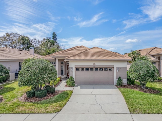 view of front of house featuring a front lawn, a tiled roof, concrete driveway, stucco siding, and a garage