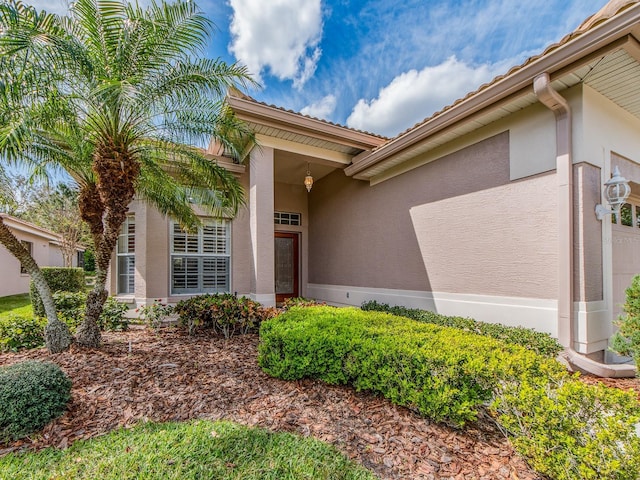 doorway to property featuring an attached garage and stucco siding