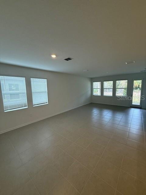 empty room featuring tile patterned flooring, visible vents, and baseboards