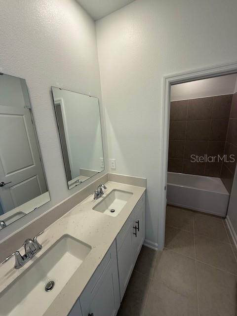 full bathroom with double vanity, tile patterned flooring, a bathtub, and a sink