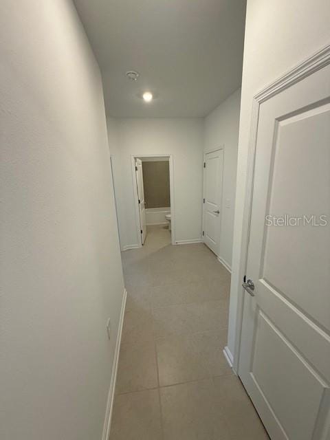 hallway featuring light tile patterned floors and baseboards