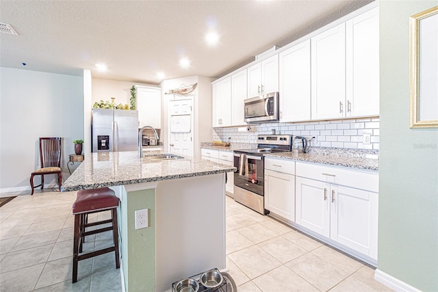 kitchen with light tile patterned flooring, tasteful backsplash, appliances with stainless steel finishes, and a sink