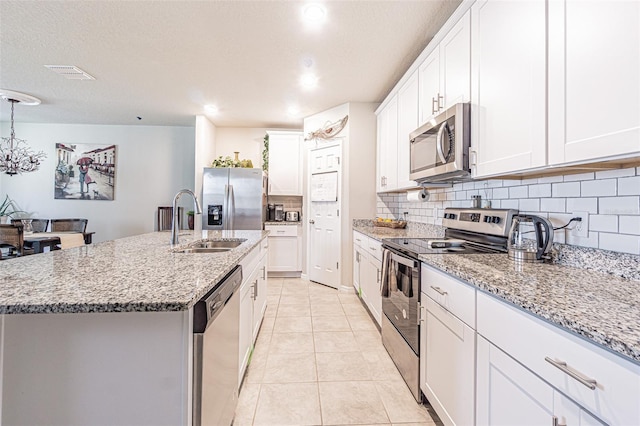 kitchen with light tile patterned floors, visible vents, a sink, stainless steel appliances, and tasteful backsplash