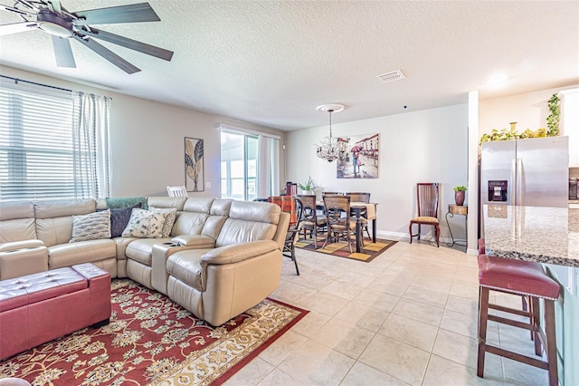 living area with light tile patterned floors, visible vents, a healthy amount of sunlight, and ceiling fan with notable chandelier