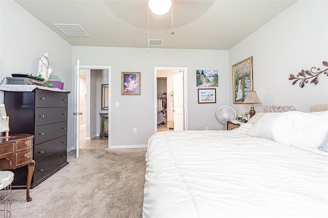 bedroom featuring visible vents, carpet floors, a textured ceiling, and connected bathroom