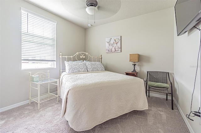 bedroom featuring a textured ceiling, a ceiling fan, baseboards, and light carpet