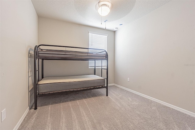 unfurnished bedroom with a ceiling fan, baseboards, a textured ceiling, and carpet flooring