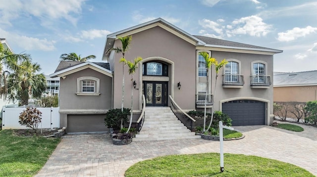 view of front facade featuring decorative driveway, french doors, a garage, and stucco siding