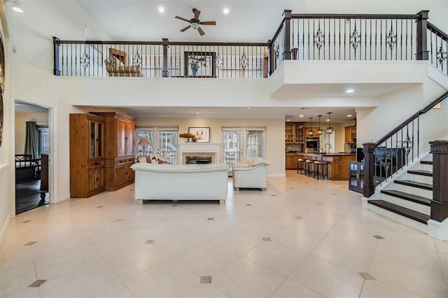 living room featuring baseboards, a ceiling fan, stairs, a fireplace, and recessed lighting