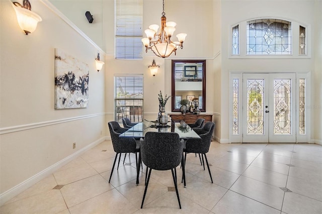 dining space with an inviting chandelier, tile patterned flooring, a high ceiling, and baseboards