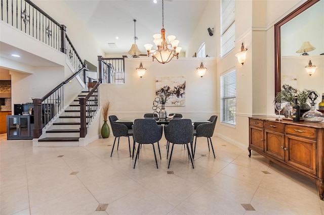 dining space featuring light tile patterned floors, stairway, a towering ceiling, a chandelier, and baseboards