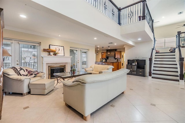 living room featuring recessed lighting, stairs, french doors, ornamental molding, and a glass covered fireplace